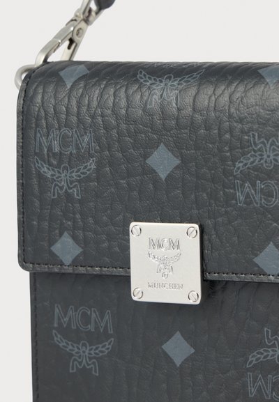 Μαύρη δερμάτινη τσάντα με υφή, με λογότυπο MCM και διαμάντι μοτίβο, που διαθέτει ασημένιο κούμπωμα και διακοσμητικά. Компакт форма σε ορθογώνιο σχήμα.