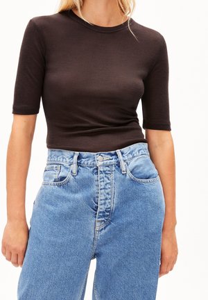 Czarny, gładki top z krótkim rękawem w zestawieniu z jasnoniebieskimi dżinsami z wysokim stanem, wyposażonymi w zapięcie na guziki oraz klasyczny fason z pięcioma kieszeniami.