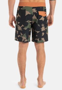 Herren-Badehosen mit einem floralen Camouflage-Muster in Schwarz, Grün und Braun. Sind mit einem einfarbigen orangen Bund und einer Gesäßtasche ausgestattet.