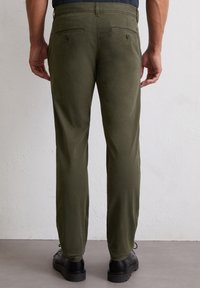 Olivgrüne Hosen mit glatter Textur, ausgestattet mit Gesäßtaschen und Knopfverschluss. Im schlanken Schnitt und mit geradem Bein geschnitten.