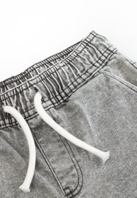 Szare szorty dżinsowe z elastycznym pasem o marszczonej fakturze i białym sznurkiem. Zawierają boczne kieszenie oraz subtelne detale w szyciu.