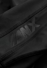 Must mustriks kangas mustas värvuses, millel on tekstureeritud must logo "NX" koos joontega. Tootel on tugevdatud õmblused servade ümber.
