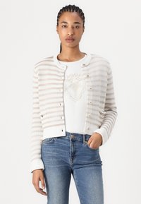 Gestreifter Strickcardigan in Beige und Weiß, mit Rundhalsausschnitt, Knopfverschluss und gerippten Bündchen. Trägt man über einem weißen Grafik-T-Shirt.