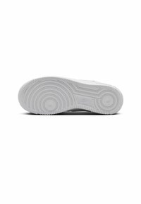 Valkoinen Nike-tennarin pohja, jossa on pyöreitä uramalleja, teksturoitu kumimateriaali ja kohokirjailtu logo lähellä kantapäätä. Siisti ja minimalistinen muotoilu.