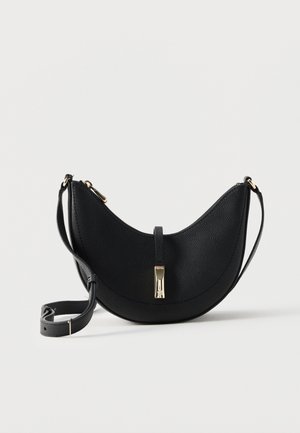 Čierna kožená crossbody taška v tvare polmesiaca so zlatým zapínaním a nastaviteľným popruhom na jednoliatom svetlom pozadí.