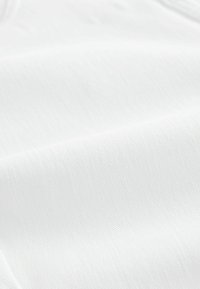 Weiches, weißes Gewebe mit glatter Textur und subtilem diagonalen Muster, das Falten und Drapierungen zeigt, ohne sichtbare Nähte oder Beschläge.