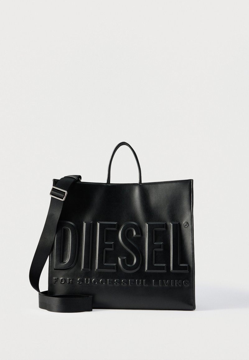 Μαύρη δερμάτινη τσάντα tote Diesel με μεγάλο ανάγλυφο λογότυπο και ρυθμιζόμενο ιμάντα ώμου σε απλό λευκό φόντο.