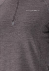 Purple athletic top with a half-zip collar, made from a textured material. Features "ENDURANCE" logo in light gray. Tailored fit.