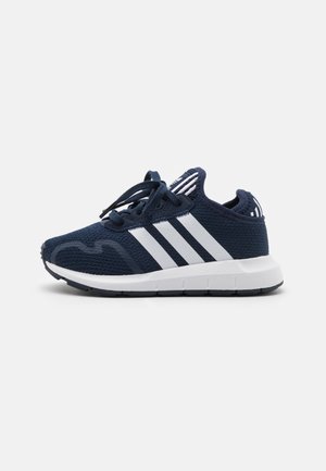 Granatowy sportowy sneaker z białymi trzema paskami po boku, białą podeszwą i czarnymi sznurowadłami, pokazany od zewnętrznej strony.