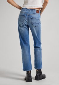Ljust blå denimjeans med rak benmodell, två bakfickor, synlig sömnad och en brun läderlapp på midjebandet.