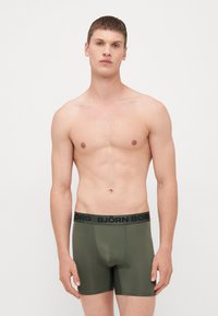 Olivnozeleni bokserice s crnim pojasom sa oznakom "BJÖRN BORG", glatke teksture, prilagođenog dizajna i srednjeg struka.