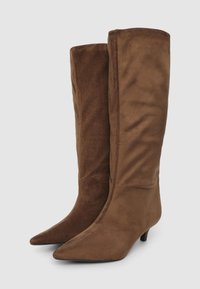 Bottes marron jusqu'aux genoux en suede doux, avec un bout pointu et un petit talon. Texture lisse avec un design ajusté et aucun matériel visible.