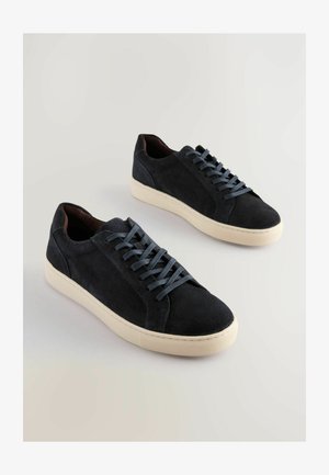 Zapatillas de ante azul oscuro con cordones azul claro y suelas de goma crema. Punta redondeada, diseño de caña baja y textura suave.