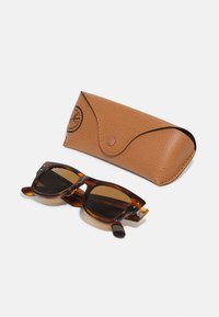 Ochelari de soare tortoise maro cu lentile maronii, însoțiți de un toc din piele texturată maro, dotat cu închidere prin apăsare și detaliu cu logo.