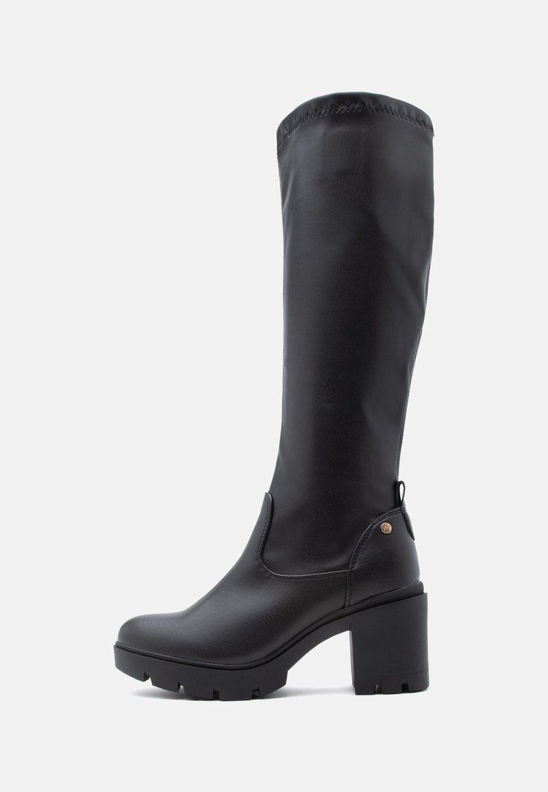 Botte haute en cuir noir avec talon bloc épais et semelle robuste, avec une petite languette à l’arrière et des détails de couture minimaux.
