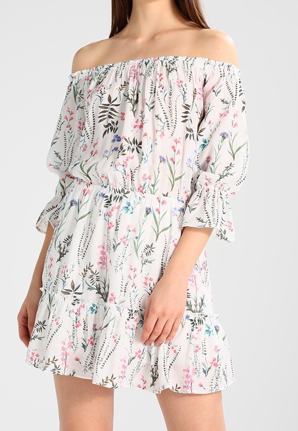 Axelklänning i lätt tyg med blommönster. Har volanger på ärmarna och fåll, åtsittande midja och mjuka pastellfärger.