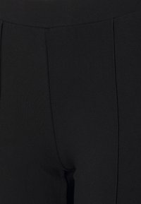 Černé elastické kalhoty s hladkým povrchem, s vysokým pasem a vertikálním prošíváním podél přední části.