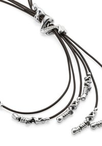 Des accents en métal argenté éparpillés sur trois brins de cuir marron foncé. Comprend un fermoir torsadé central pour une fermeture sécurisée.