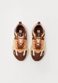 Több színű sneaker, barna és bézs felsőrésszel, hálós és velúr textúrával, kerek orral, párnázott gallérral és kontrasztos fűzőkkel.