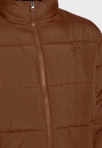Brązowa kurtka puchowa z wysokim kołnierzem, frontowym zamkiem błyskawicznym, pikowaną teksturą oraz małym trójkątnym logo na lewej części klatki piersiowej.