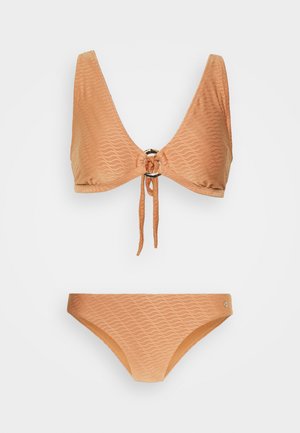 Conjunto de biquíni de duas peças em um tecido texturizado de cor marron claro. O top apresenta um decote em V profundo, com um laço ajustável e um detalhe circular; a parte de baixo possui um design correspondente.