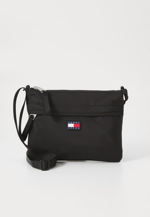 Black nylon shoulder bag with a zip closure, adjustable strap, and a rectangular logo patch featuring red, white, and blue accents.