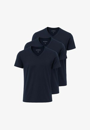 Marineblå v-hals t-shirt i let bomuld, parret med slim-fit blå jeans og hvide sneakers, hvilket skaber et afslappet look med minimale detaljer.