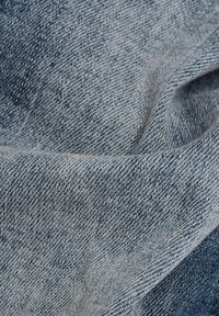 Tela de mezclilla azul con un tejido ajustado visible y sutiles pliegues que crean textura y profundidad.