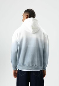 Hoodie met een ombreverloop van wit naar lichtblauw. Zachte stof, comfortabele pasvorm en zichtbare stiksels bij de manchetten en zoom.