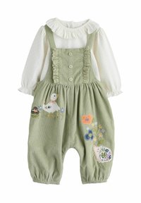 Grønne fløjlsfutter med broderede ænder og blomsterdesigns. Hvid bluse med polka-dots og flæser ved udskæringen. Tryknapper foran.