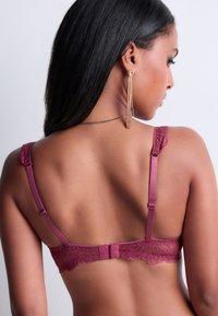Soutien-gorge bordeaux avec des bordures en dentelle, des bretelles en satin et un matériel ajustable. La vue arrière met en valeur de élégantes bords festonnés et une fermeture à crochets.