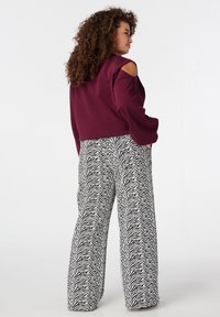 Bordeauxrood cropped sweatshirt met cold shoulder ontwerp, gecombineerd met zwart-witte wijduitlopende broek met zebraprint. Gladde stof, losse pasvorm.
