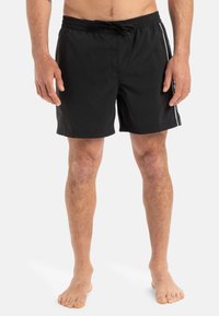 Bañadores negros con una cintura elástica y cordón, franjas laterales blancas en contraste y una textura suave.