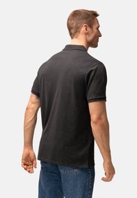 Kulgrå polo t-shirt med klassisk krave, korte ærmer og sidetern, parret med blå jeans. Glat tekstur og tætsiddende design.