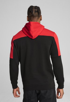 Sudadera negra con acentos rojos en los hombros y la capucha. Presenta un corte holgado y mangas largas, fabricada con un tejido suave y texturizado.