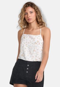 Hvid blomstret camisole med tynde stropper, prydet med pastelfarvede blomster spredt ud over. Samlet med høj talje sorte shorts og sølvknapper.
