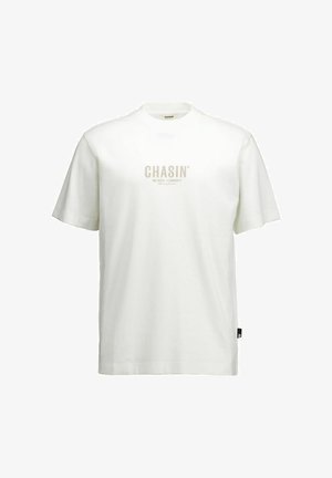 Weißes kurzärmeliges T-Shirt mit Rundhalsausschnitt und zentral platziertem beigem Text "CHASIN' AMS BASED - C-COMMUNITY" auf der Vorderseite.