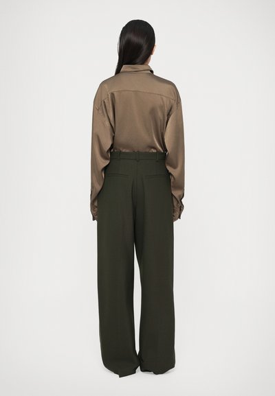 Cămașă din satin maro cu guler; pantaloni largi de culoare verde măslin, cu talie înaltă și buzunare pe spate; textură netedă pe toată suprafața.