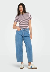 Gestreepte korte mouwen t-shirt in bordeauxrood en wit, gecombineerd met lichtblauwe wijde jeans en witte sneakers met blauwe accenten.