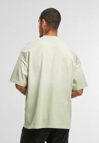 Lys grøn oversized t-shirt i blødt stof, med korte ærmer, rund halsudskæring og en afslappet pasform. Ingen synlige mønstre eller detaljer.