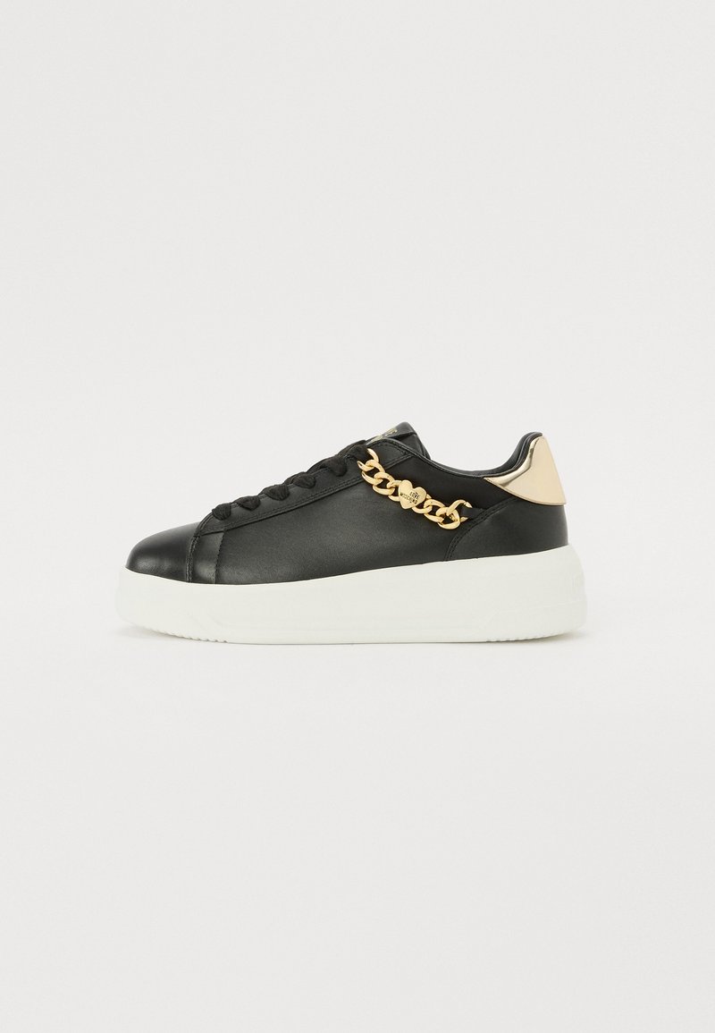 Svart lädersneaker med vit plattformssula, med ett gold chain-accent på sidan och en guld-accentuerad häl.