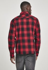 Rood en zwart geruite blouse met een button-down kraag, lange mouwen en een rechte achterkant. Zachte stof met een geruit patroon.