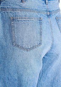 Svetlomodré džíny z denimu s detailom zadnej kapsy. Obsahujú jemnú textúru a kontrastné šitie pozdĺž okrajov kapsy. Vysoký pás.