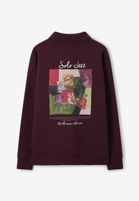 Bordeauxfarbener Pullover mit einem großen, bunten Grafikdruck auf der Rückseite, der abstrakte Musiker zeigt. Mit Kragen und langen Ärmeln.