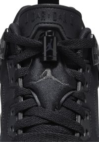 Gros plan sur la languette noire de la basket Air Jordan avec logo Jumpman noir, lacets noirs et texte embossé "JORDAN".