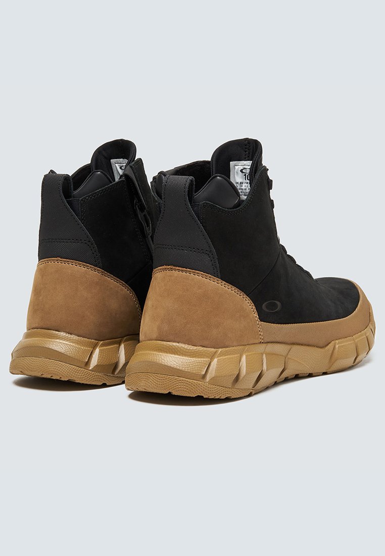 Zapatos de ante negro y goma con acentos marrones, diseño de caña alta, superficie texturizada y una suela moldeada con surcos para tracción.