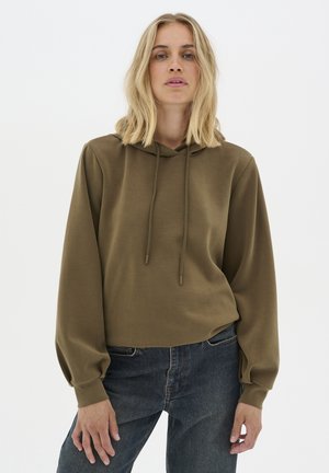 Olivgrüner Kapuzenpullover mit einer Fronttasche, Kordelzug und lockeren Ärmeln, kombiniert mit blauen hochgeschnittenen Jeans. Glatte Textur.