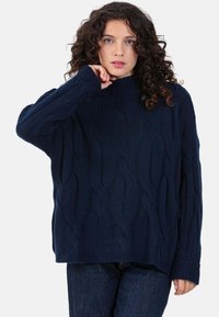 Marineblauer Strickpullover mit Zopfmuster, geripptem Rollkragen und gekämmten Ärmeln; lockere Passform und strukturierte Oberfläche.