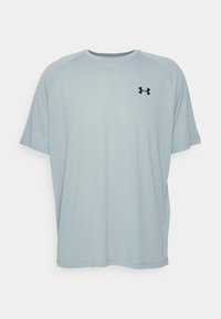 Ljusblå t-shirt med kort ärm för sport som är tillverkad av mjukt material. Den har en rund halsringning och en svart Under Armour-logotyp på bröstet.