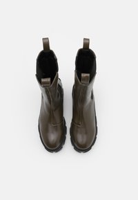 Bottes chelsea en cuir marron avec une texture lisse, des panneaux latéraux élastiques et des languettes ; dotées d'une semelle en caoutchouc noir durable.